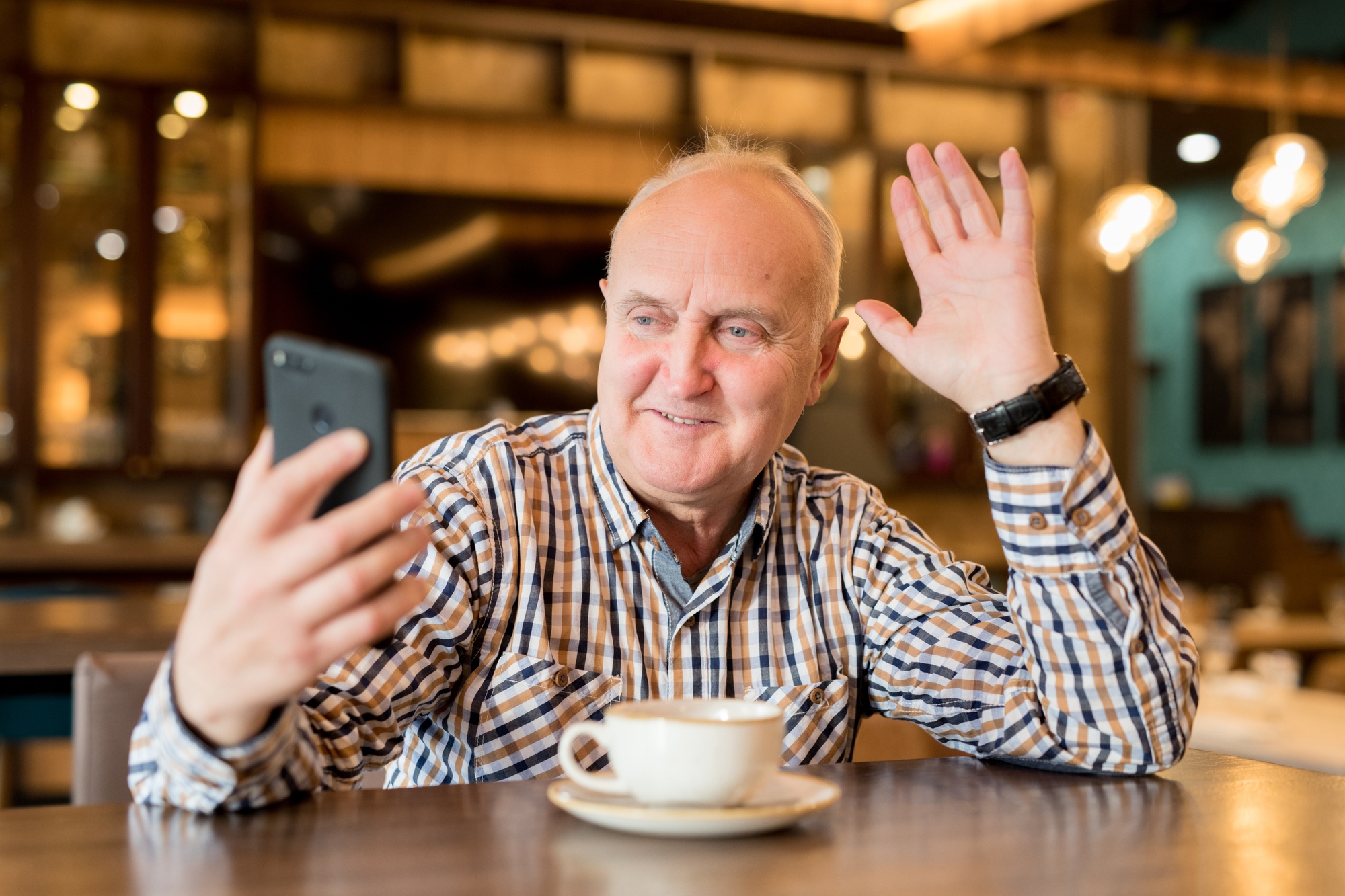 Cheerful chubby man speaking via video link in cafe